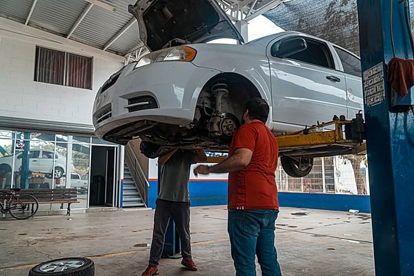 Car raised on a two-post lift inside a service bay